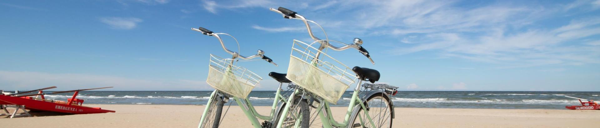 Due biciclette sulla spiaggia con barche di salvataggio sullo sfondo.